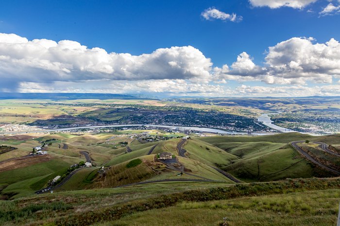 Sunny view of Lewiston, Idaho from the top of Lewiston Hill. with green hills in foreground