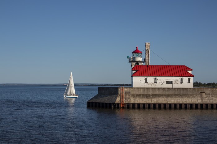 A breakwater lighthouse on Lake Superior with a sailboat.