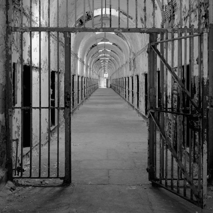 A black and white photo of the interior of an abandoned jail.