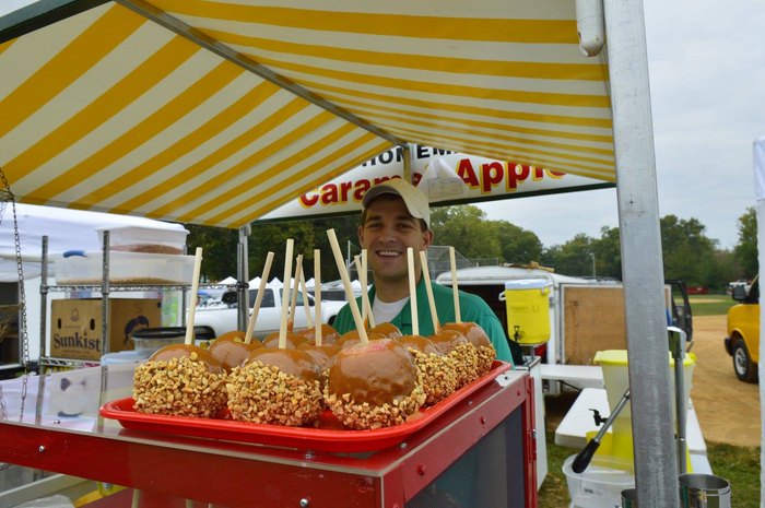 A smiling man serves up delicious caramel apples.