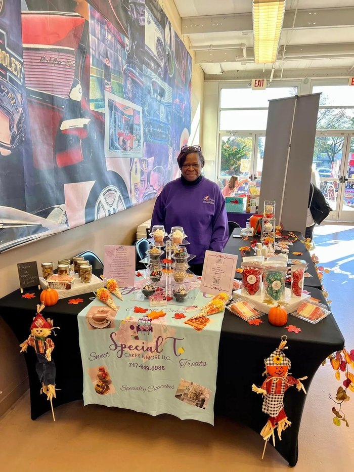A proud vendor stands in front of her craft table.