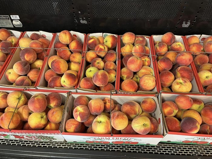 A row of fresh peaches in cartons.