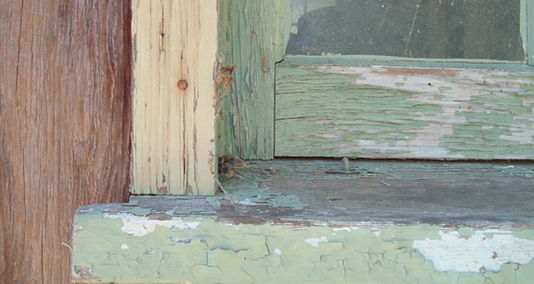 The cracked and peeling paint surface of an outside window sill.