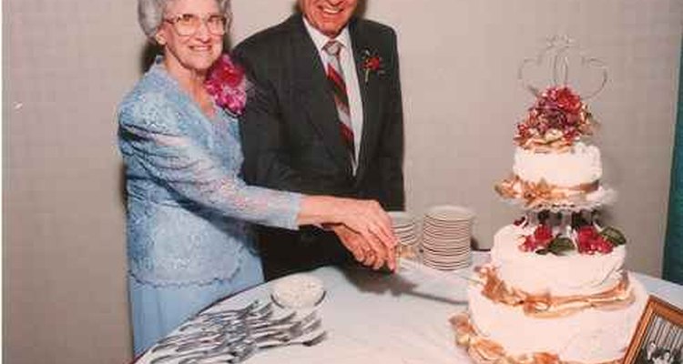 Happy couple cutting their golden anniversary cake.