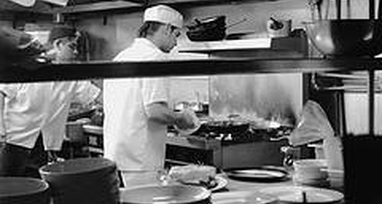 Los cocineros de línea trabajan en una estación de la cocina de un restaurante.