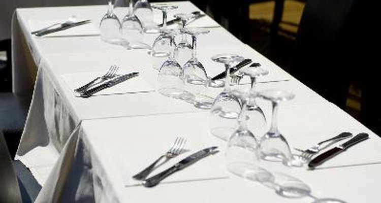 Una anfitriona de restaurante debe asegurarse que la mesa está ordenada y lista para los próximos comensales.
