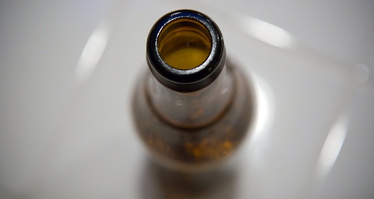 Una botella de cerveza necesita ser limpiada por una lavadora de botellas mediante un chorro de agua.