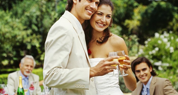 newlywed couple holding glasses of wine at their wedding reception