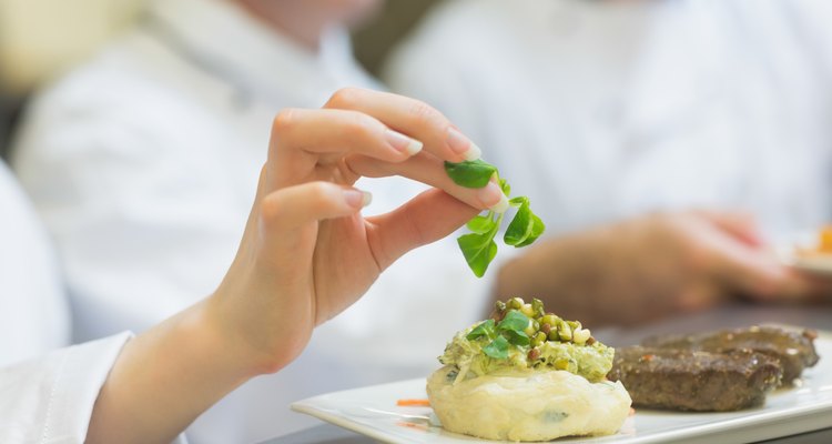 Female chef garnishing a plate with steak