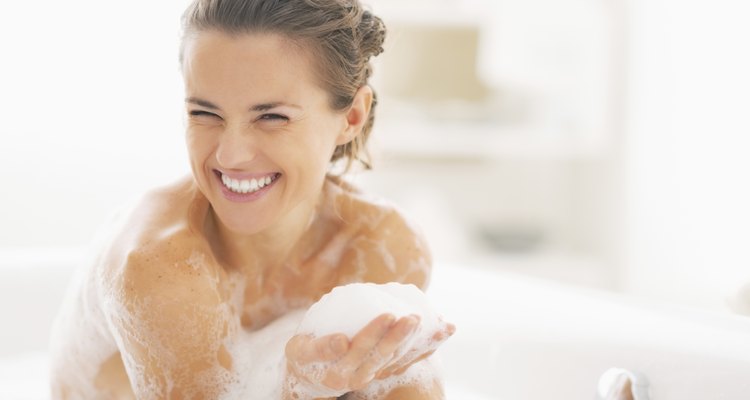 portrait of happy young woman playing with foam in bathtub