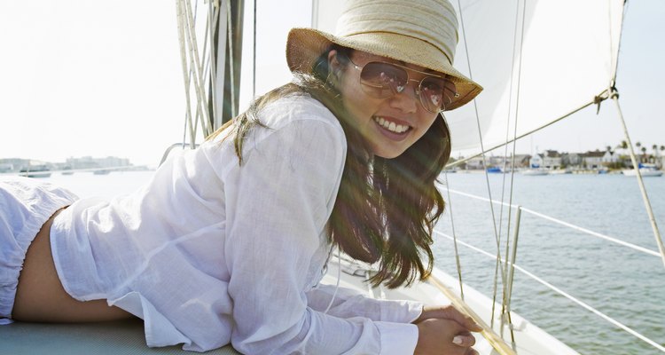 Portrait of a Young Woman in a Sunhat and Sunglasses Lying on the Deck of a Yacht