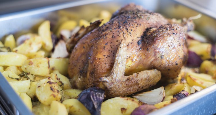 Whole chicken on a bed of potatoes and onions