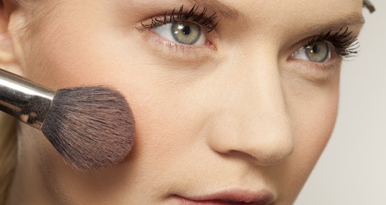 Young woman applying make up with brush, close up