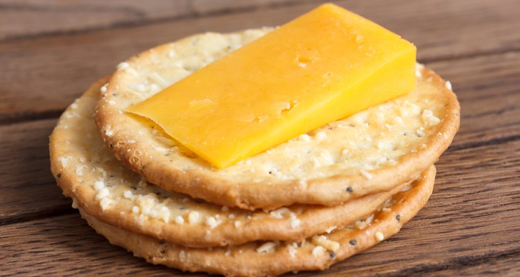 Three golden cheese crackers on wood. With cheese.