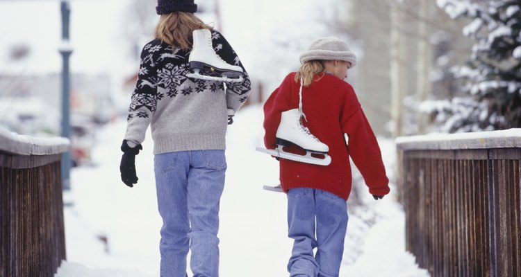 Mother and daughter (13-14) walking with ice skates over bridge in snow