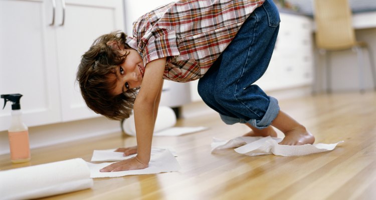Boy (5-7) polishing floor with paper towel under hands and feet