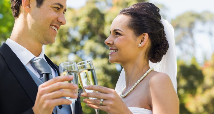 Newlywed toasting champagne flutes at park