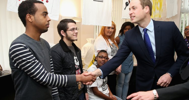 El príncipe William saluda a un trabajador de caridad.