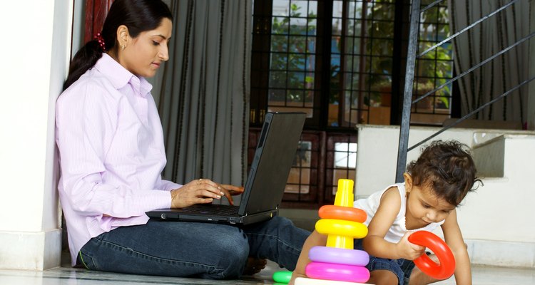 Mujer trabaja en la computadora portátil junto a un niño.