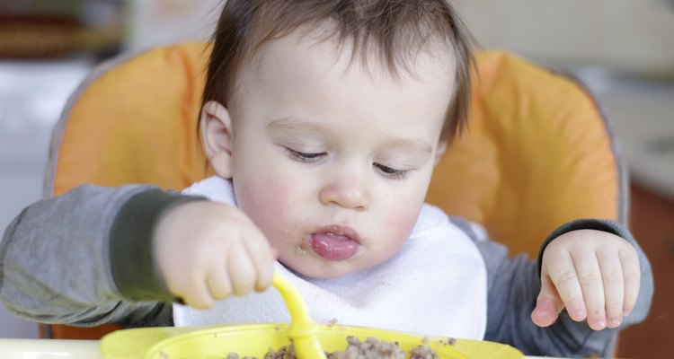 Bebé comiendo puré de alimentos en un plato pequeño.