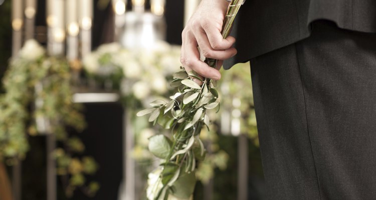 Grief - man with white roses at urn funeral