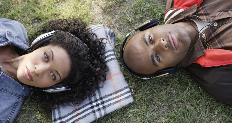 African couple listening to headphones in grass. Vertical composition