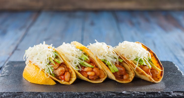 Mexican tacos with meat, beans, avocado, cheese and tomato sauce