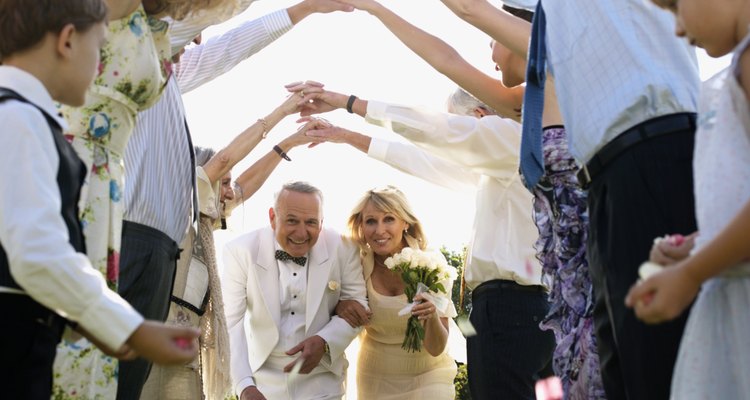 Bride and groom walking under arms of wedding guests