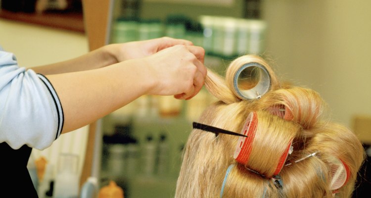 Close-up of a female hairdresser adjusting curlers in a mid adult woman's hair