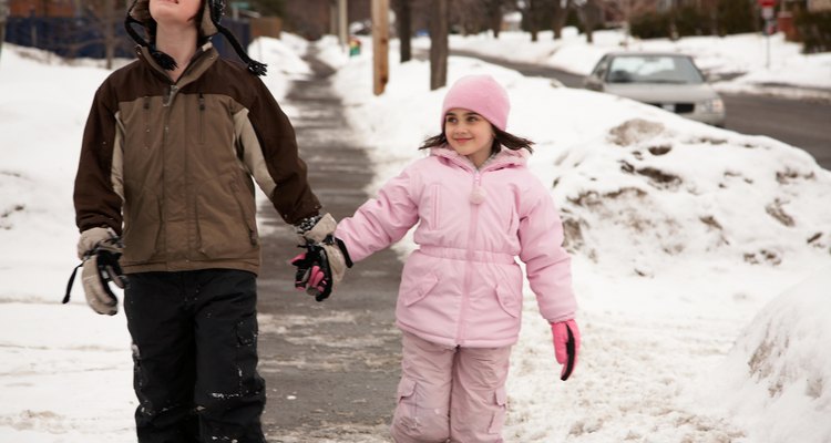 Brother and sister walking on sidewalk in winter