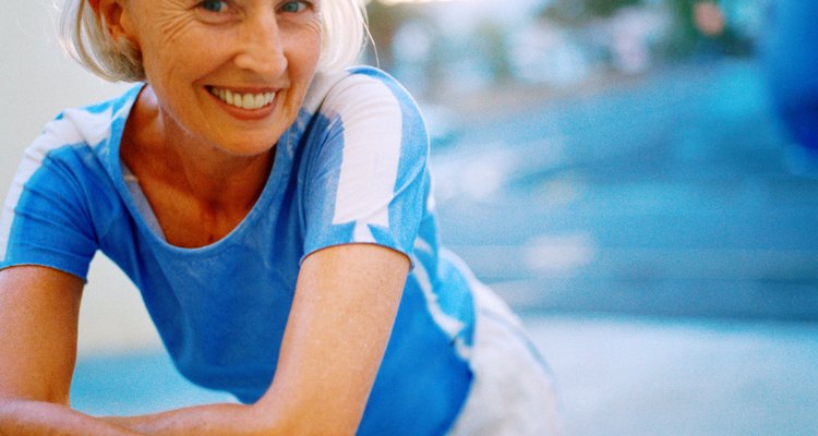 Portrait of an elderly woman smiling leaning forward on bicycle handlebars