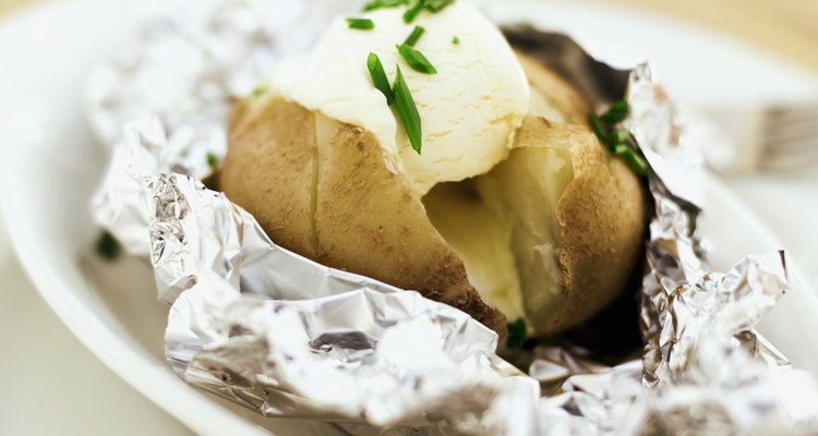 close-up of a baked potato served with sour cream in foil