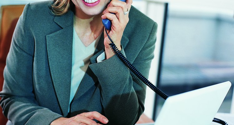 Mature CEO Sitting at Her Desk and Using a Laptop and a Phone