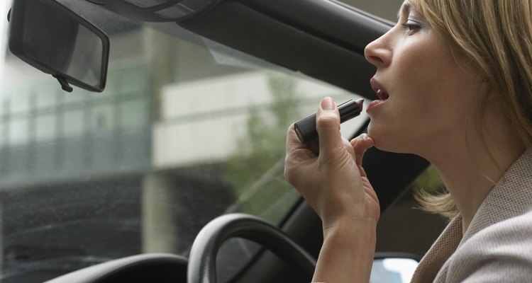 Woman Sitting Applying Make-up in a Vehicle Mirror