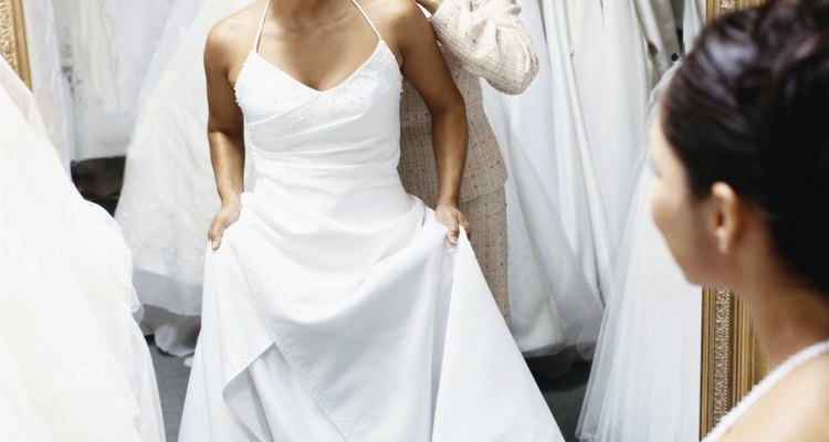 Senior Woman Helping Her Daughter Try on a Wedding Dress in Front of a Mirror in a Bridal Shop