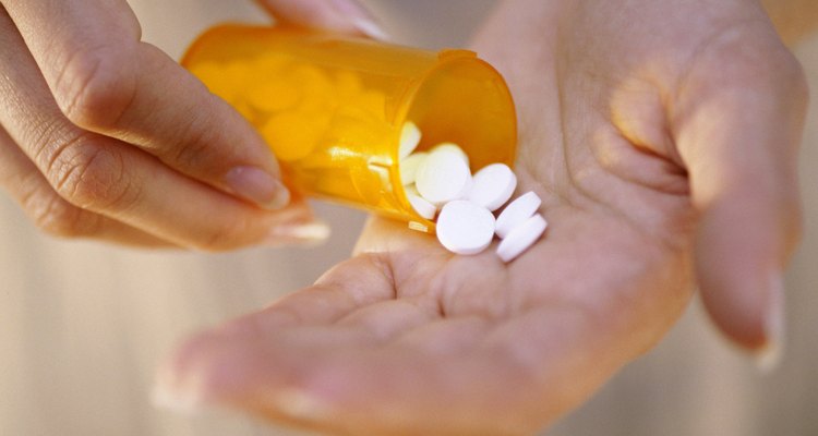 Close-up of a person's hand holding a bottle of pills