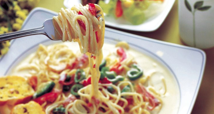 Una salsa de parmesano cubre pasta primavera.