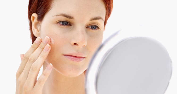 Young woman looking at her face in a mirror