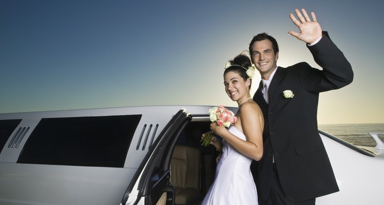 Newlyweds smiling by limousine