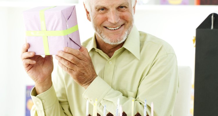 portrait of an elderly man holding up a present for a birthday celebration