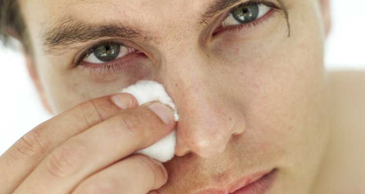 portrait of a young man cleaning his face with cotton wool