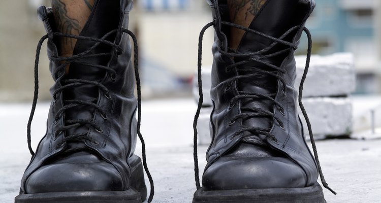 A person with tattooed legs wearing black boots