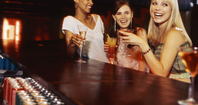Three young women at the bar counter holding drinks
