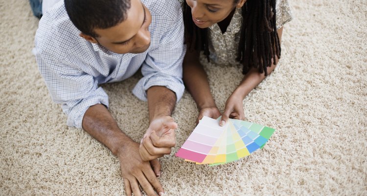 Una pareja ve muestras de pintura en la alfombra.
