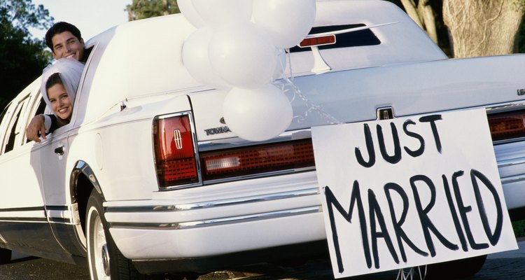 Newlywed couple waving from a limousine