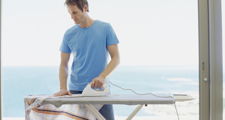 Young man ironing a shirt