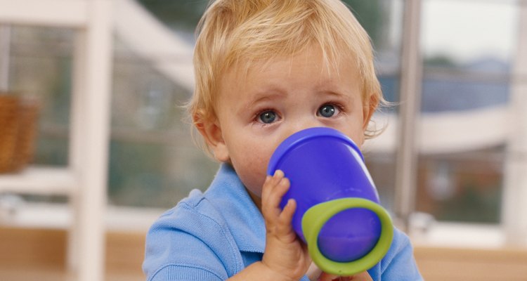 Un bebé que toma leche en su vaso.