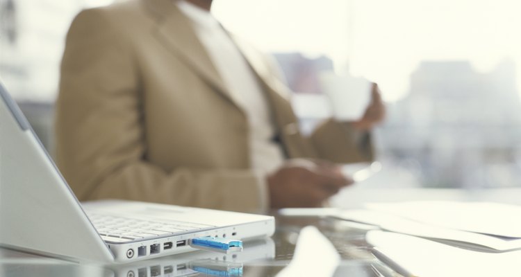 Businessman holding coffee cup, laptop on desk