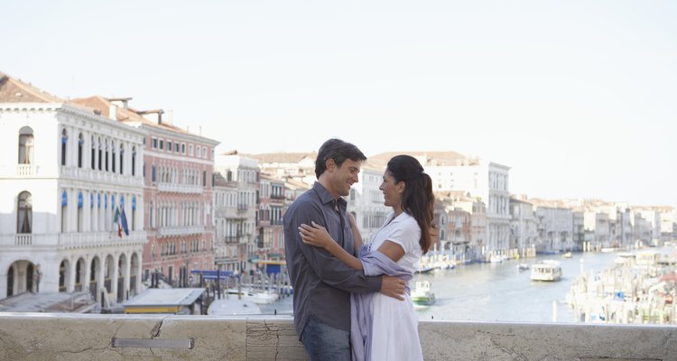 Italy, Venice, couple embracing on bridge over canal, smiling
