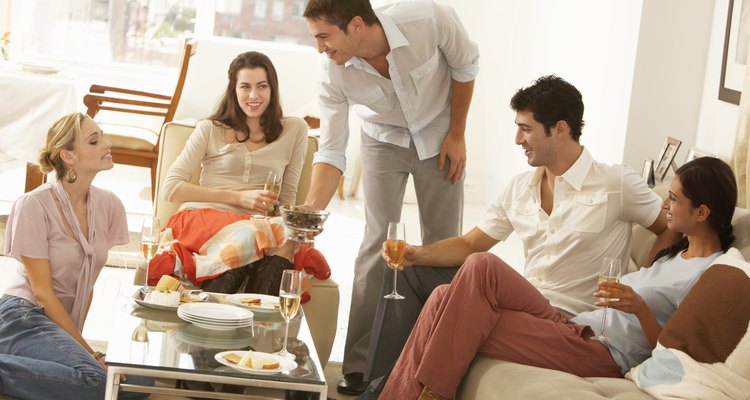 Group of young people gathered around coffee table, drinking champagne